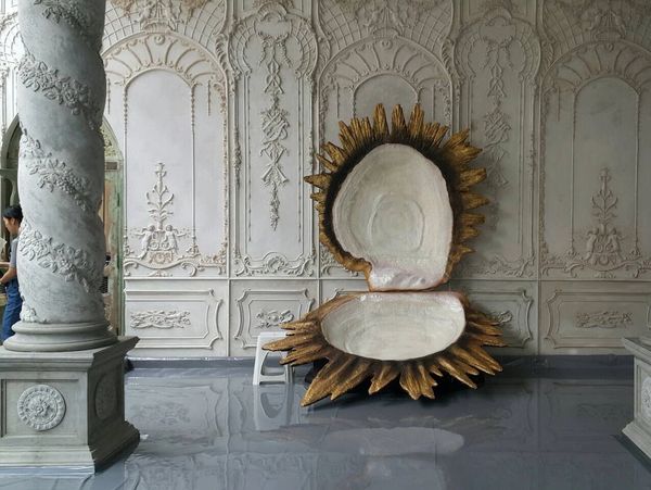 Large decorative shell sculpture in an ornate room with intricate wall designs and pillars.