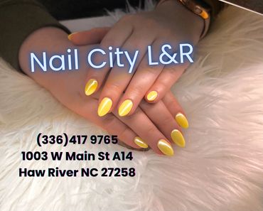 Hands with bright yellow manicured nails on a fluffy white surface.