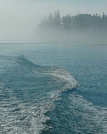 Dramatic wake from a boat leaving an island in the fog