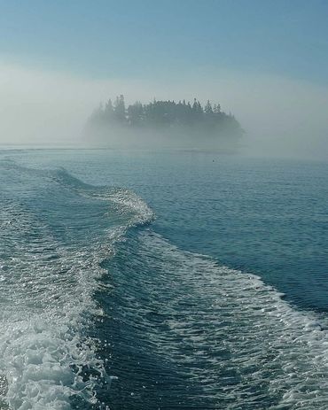 Dramatic wake from a boat leaving an island in the fog