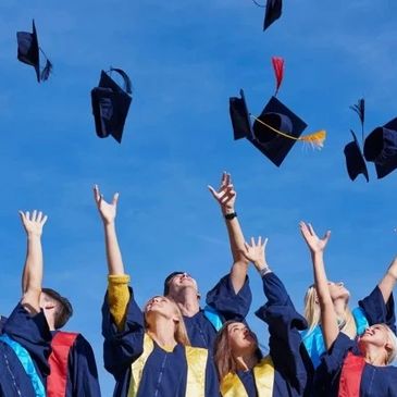 Graduates joyfully tossing their caps into the bright blue sky.