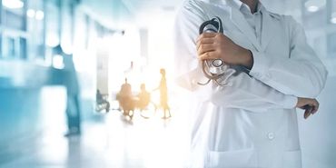 Doctor holding a stethoscope in a bright hospital corridor.