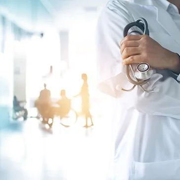 Doctor holding a stethoscope in a bright hospital corridor.