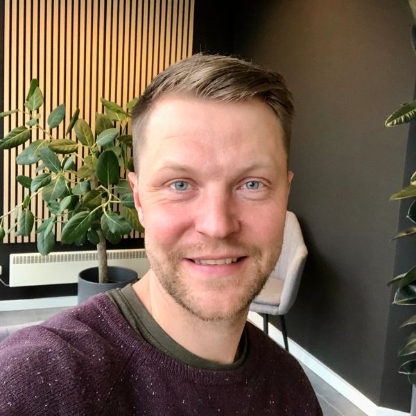 Smiling man with blue eyes in modern indoor setting with plants.