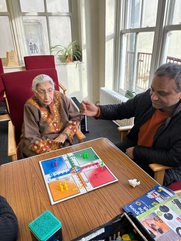 An elderly woman and a man playing a board game in a bright room.