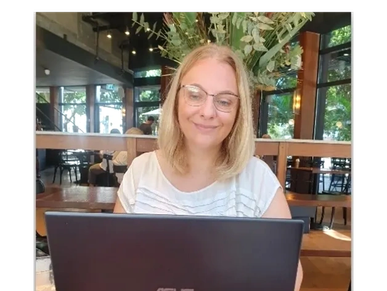 A woman working on a laptop in a cozy cafe with plants.