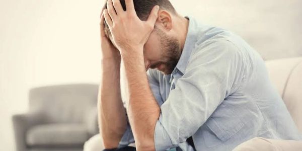 Man sitting with head in hands expressing stress.