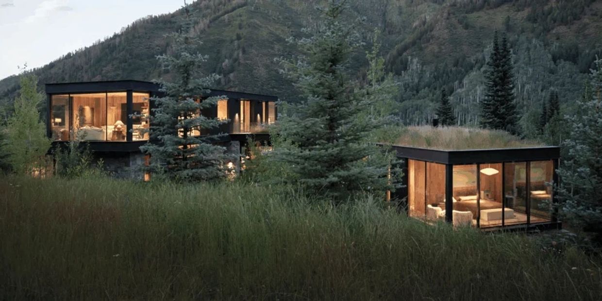 Modern glass houses illuminated at dusk in a forested mountain landscape.