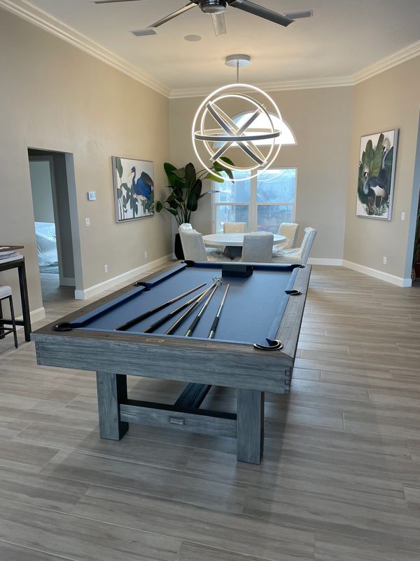 Modern game room with a pool table, round dining area, and elegant lighting.