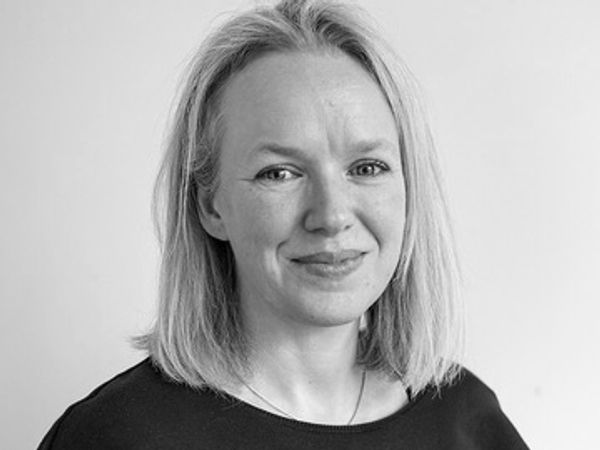 A headshot of Kat - who is a white woman with shoulder length blonde hair and blue eyes. She is smil