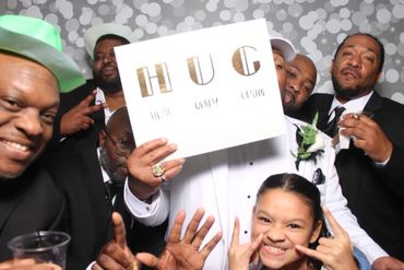 Group photo with men in suits and a girl holding a 'HUG' sign.