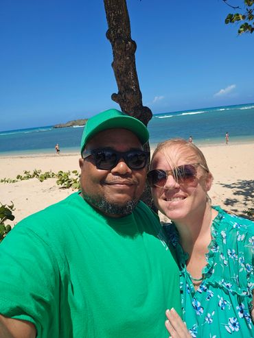 Couple smiling at the beach with clear blue sky and ocean in the background.