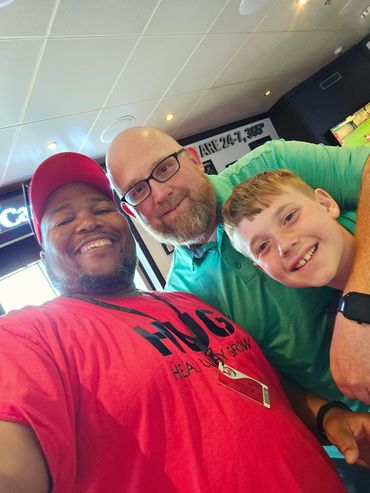 Three smiling people posing closely for a selfie indoors.