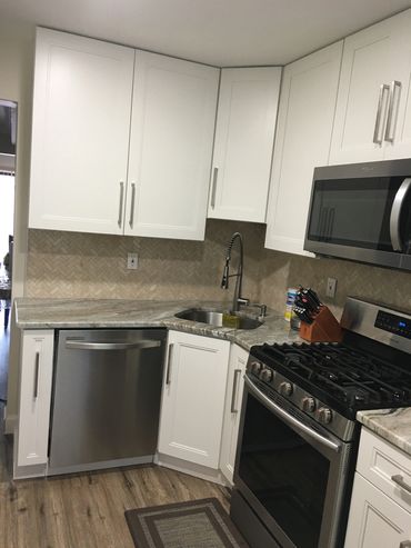 Modern kitchen with stainless steel appliances and white cabinets.