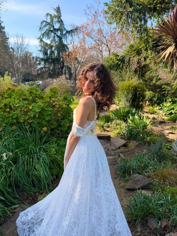 Woman in a white dress smiling in a garden.