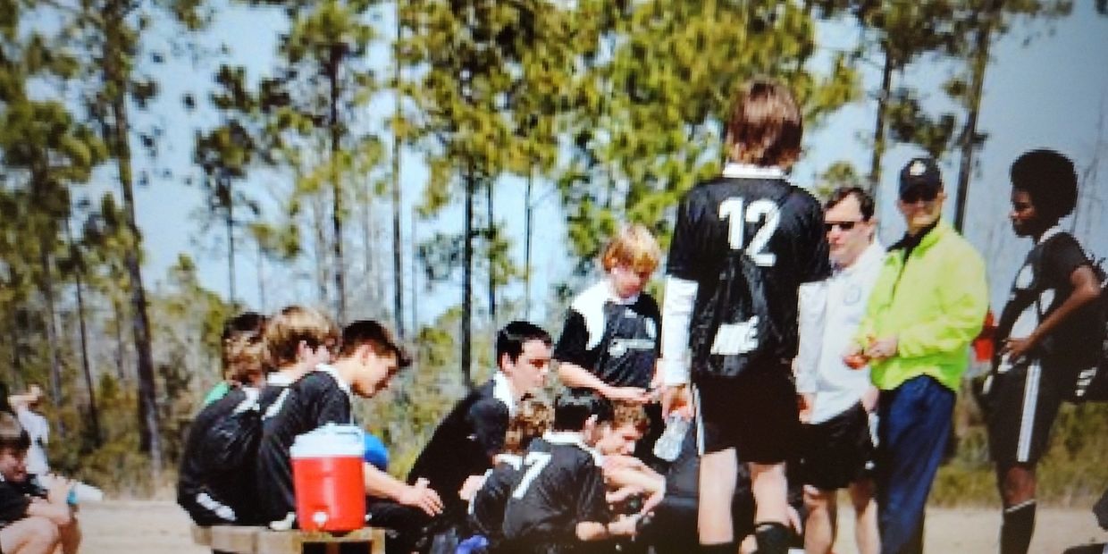 Youth soccer team in black jerseys during a break outdoors.