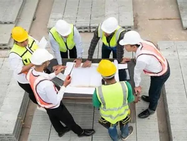 Construction workers and engineers reviewing plans on a building site.