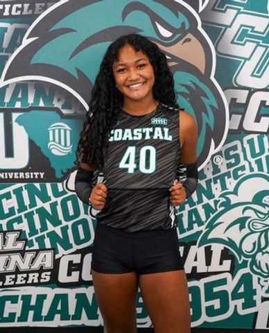 Smiling female athlete in Coastal Carolina volleyball uniform posing confidently.