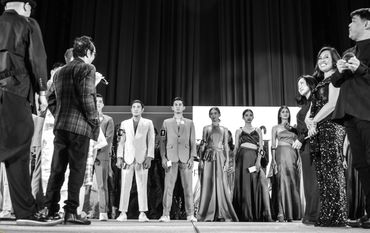 Contestants and hosts on stage during a formal event or competition.