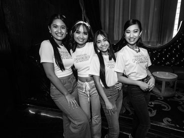 Four young women smiling and posing together in matching "Young Faces to Watch" shirts.