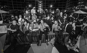 Group of photographers posing with cameras and tripods at night event.
