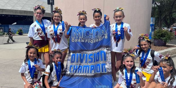 Young cheerleaders proudly display medals and a division champion banner.