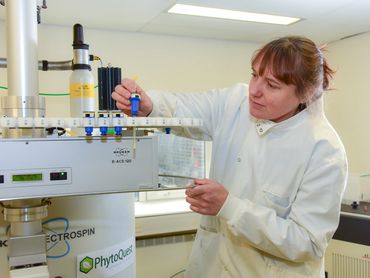 Scientist working with NMR spectrometer in a laboratory setting.