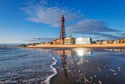 Blackpool Tower overlooking the beach with a blue sky.
