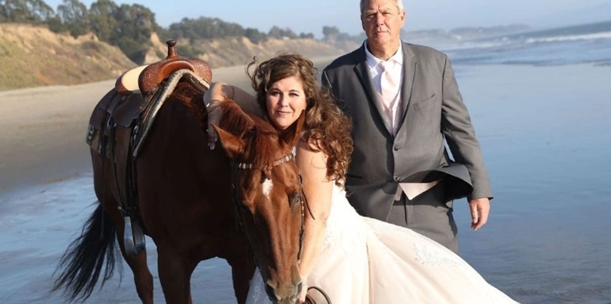 Larry and Julie on their wedding day at the beach with their horse Vegas.