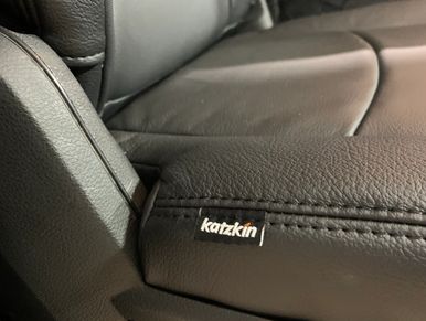 Close-up of black Katzkin leather car seat upholstery with visible stitching.