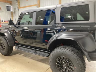 Black and grey off-road SUV with large tires in a garage.