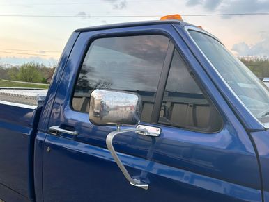 Close-up of blue pickup truck door with large side mirror and amber light on top.