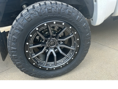 Close-up of a rugged off-road tire and alloy wheel on a white vehicle.