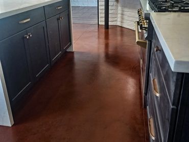 Staining and polishing concrete flooring in residential kitchen with blue cabinets and marble floor