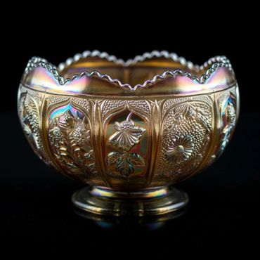 Ornate iridescent decorative bowl with floral patterns on a black background.