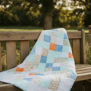 Colorful patchwork quilt draped over a wooden bench outdoors.