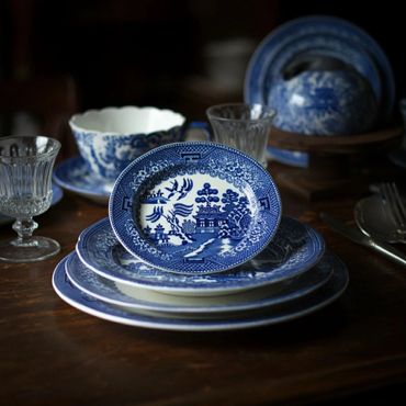 Blue and white patterned china plates and cups arranged on a wooden table.