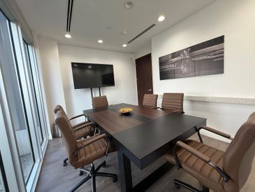 Modern conference room with brown chairs and a large black table.