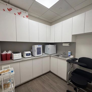A clean medical or dental prep room with white cabinets and equipment.