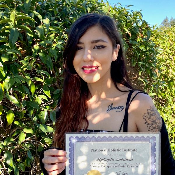 Young woman holding a diploma outdoors.