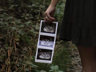 Person holding ultrasound images in a natural outdoor setting.