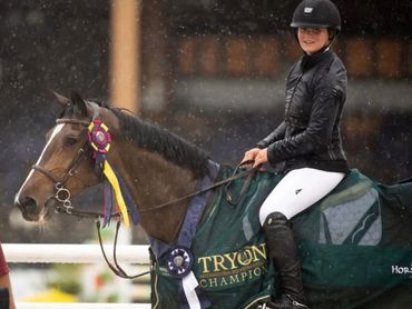 Horse rider and a man posing with a champion horse in the rain.
