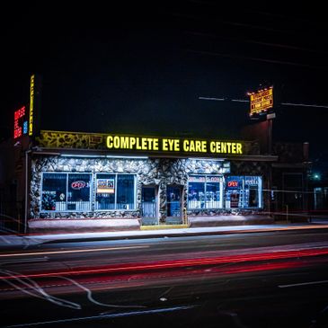 Night view of Complete Eye Care Center with light trails from passing cars.