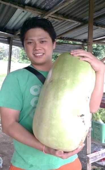 Man holding a large green squash, smiling.