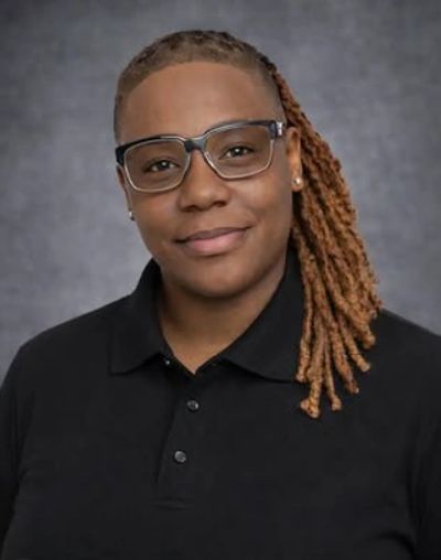 Person with glasses and dreadlocks smiling.