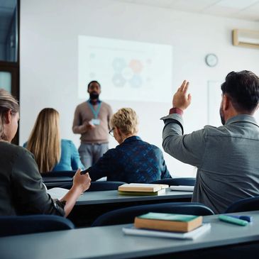 A group of people in a training room with a trainer standing in front of a presentation slide.