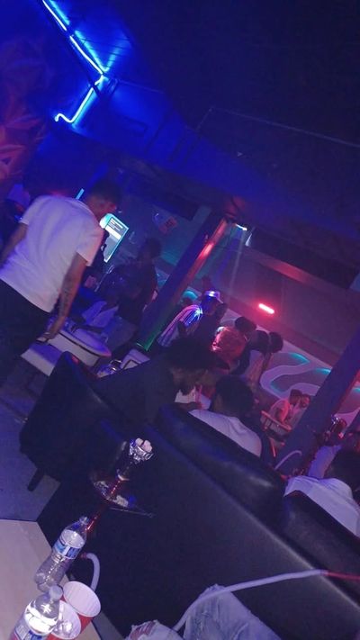 Nightclub rooftop party with string lights, music, and a city skyline in the background.