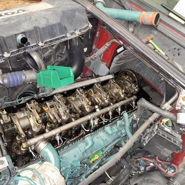 Volvo engine with the valve cover removed revealing rocker arms and camshaft.