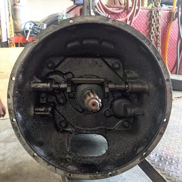 Close-up of a greasy mechanical part inside a workshop setting.