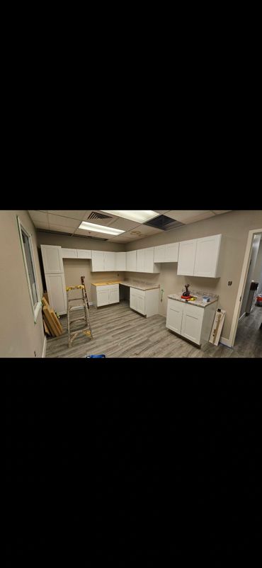 Newly installed white kitchen cabinets and wood flooring with construction tools.